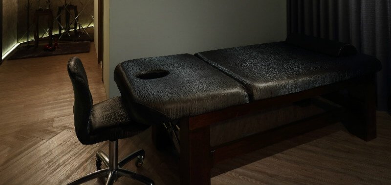 Gray massage table on wooden floor