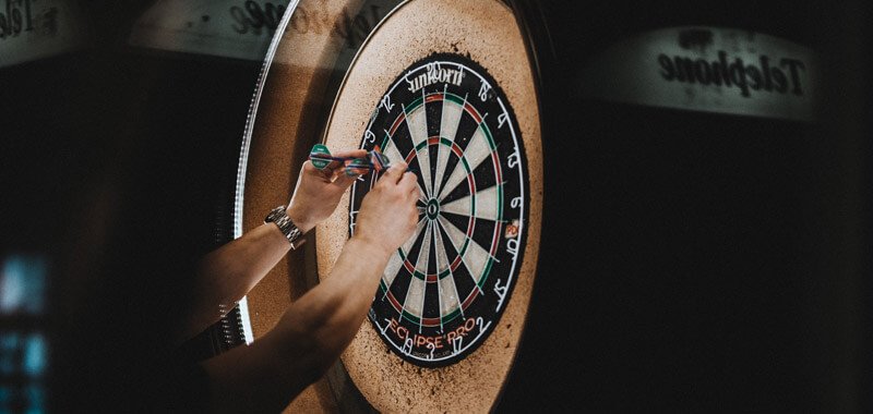 Person pulling darts out of board