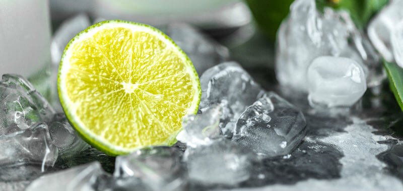 Melting ice cubes next to half a lime