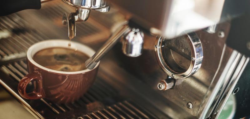 Espresso cup being filled by barista machine